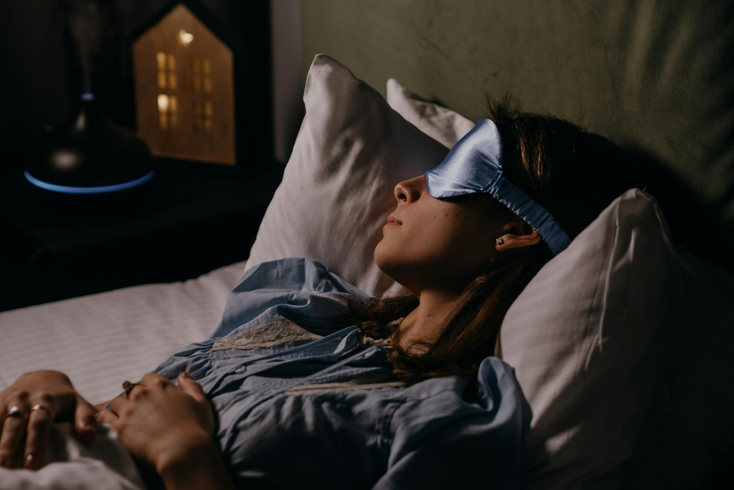 Femme adulte dormant paisiblement dans une chambre à l'ambiance zen et sombre.